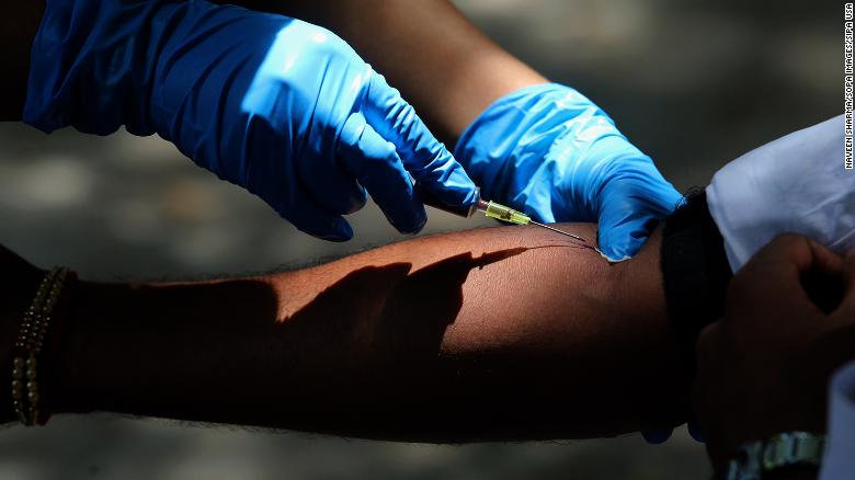 A medical Personnel collecting a blood sample from a man during the tests.